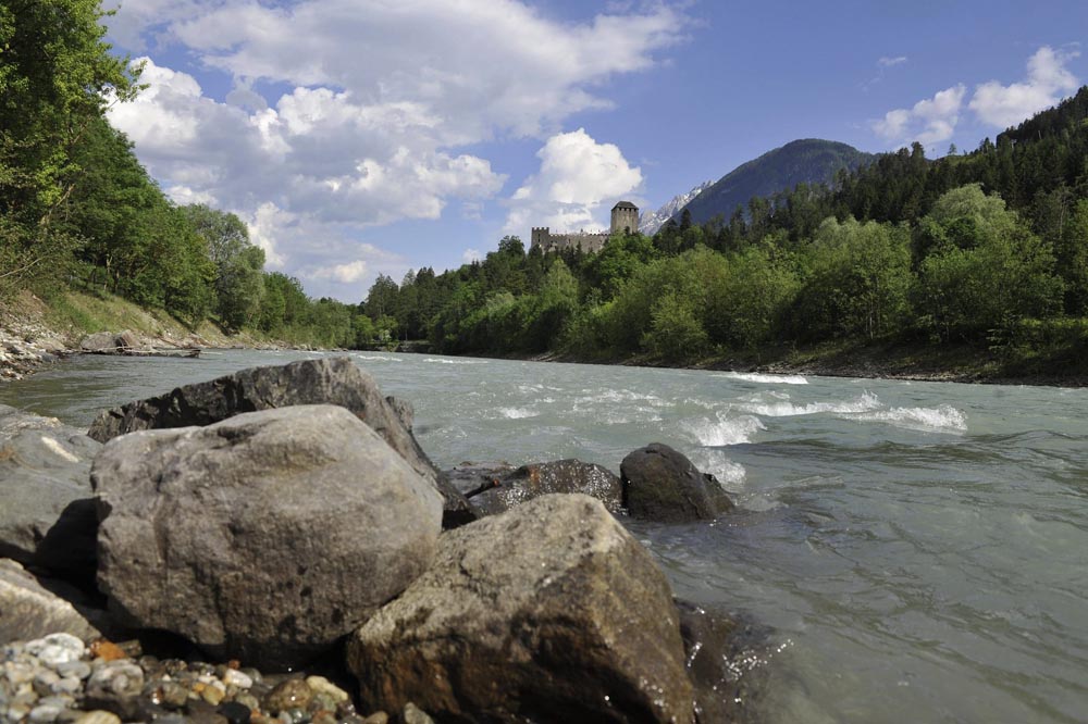 Schloss Bruck in Lienz aufgenommen von einem Fluss im Tal